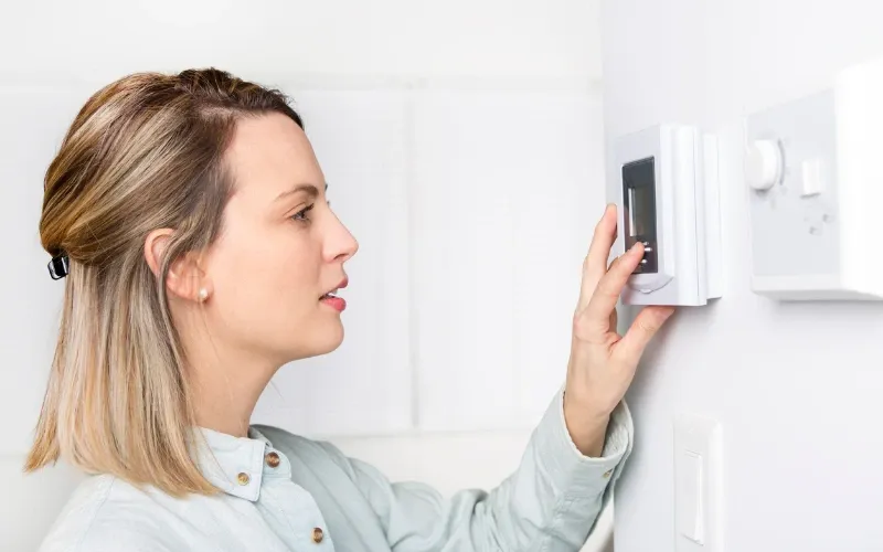 Woman checking her thermostat.