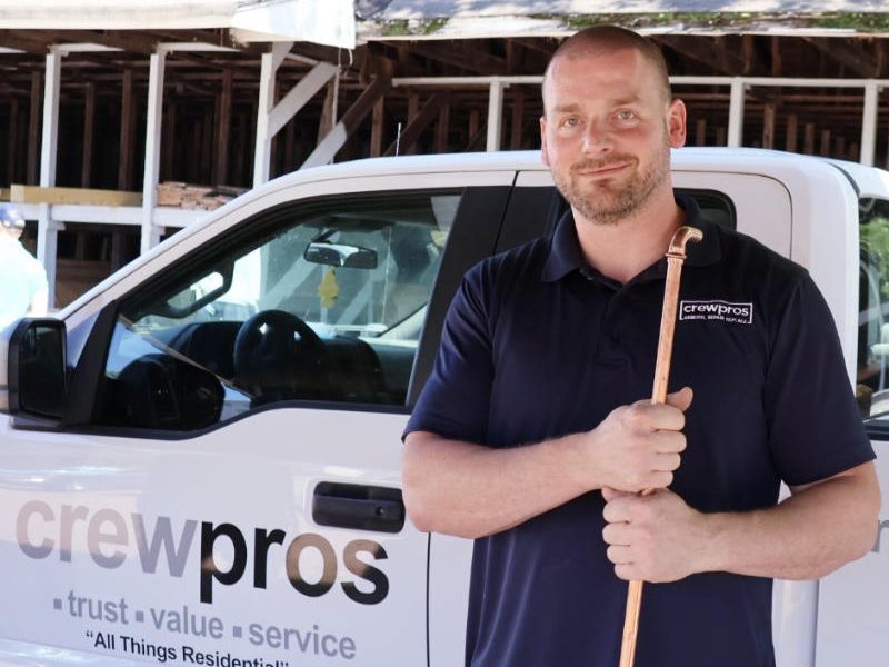 CrewPros technician holding a copper water pipe.
